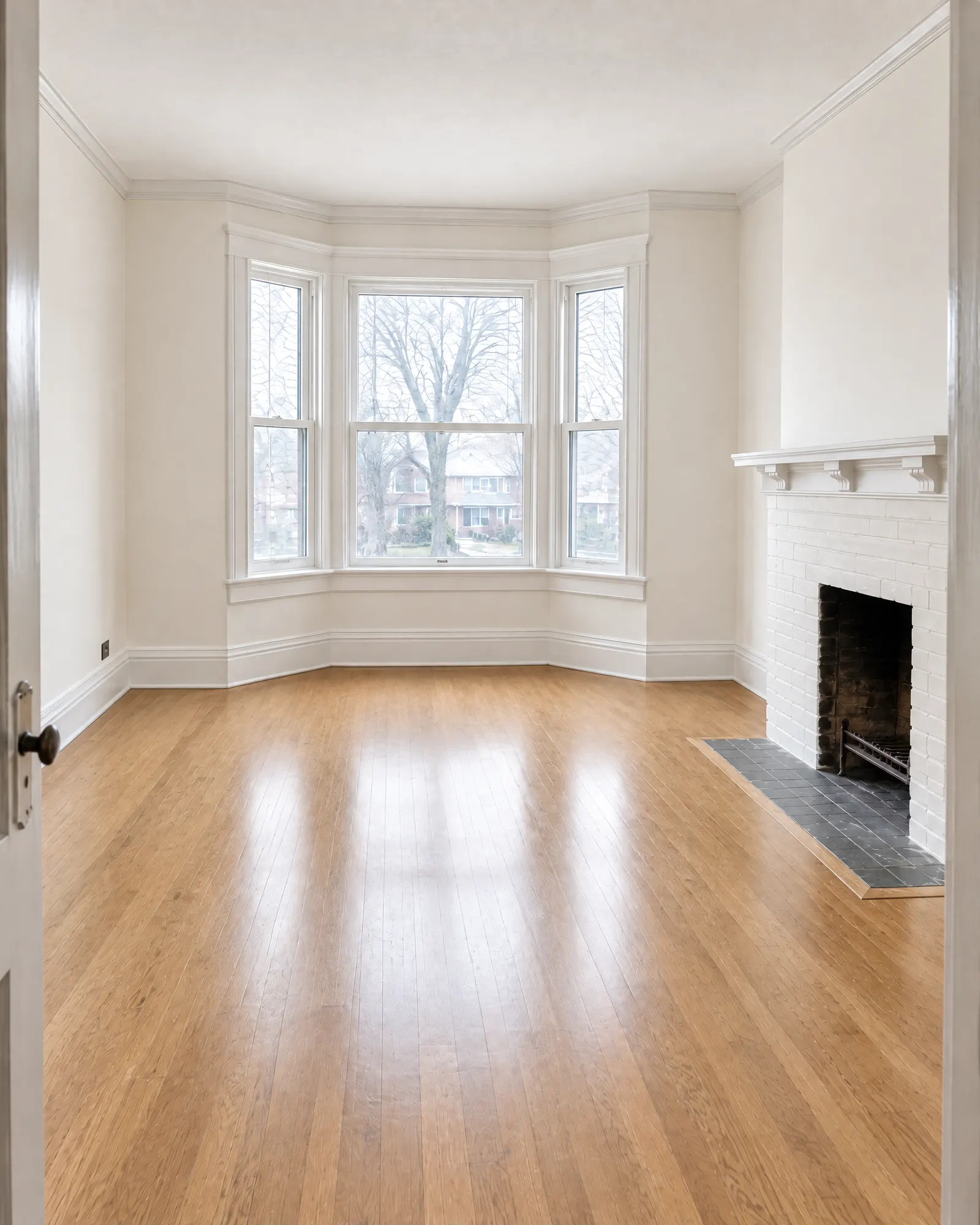Front room of a semi-detached house, faded green walls and painted brick fireplace, before and after repainting (after)
