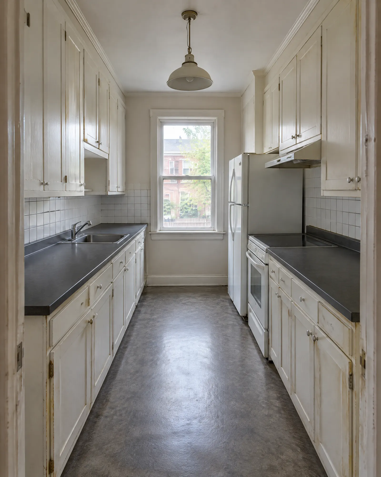 Galley kitchen from the doorway, before and after cabinet refinishing (before)