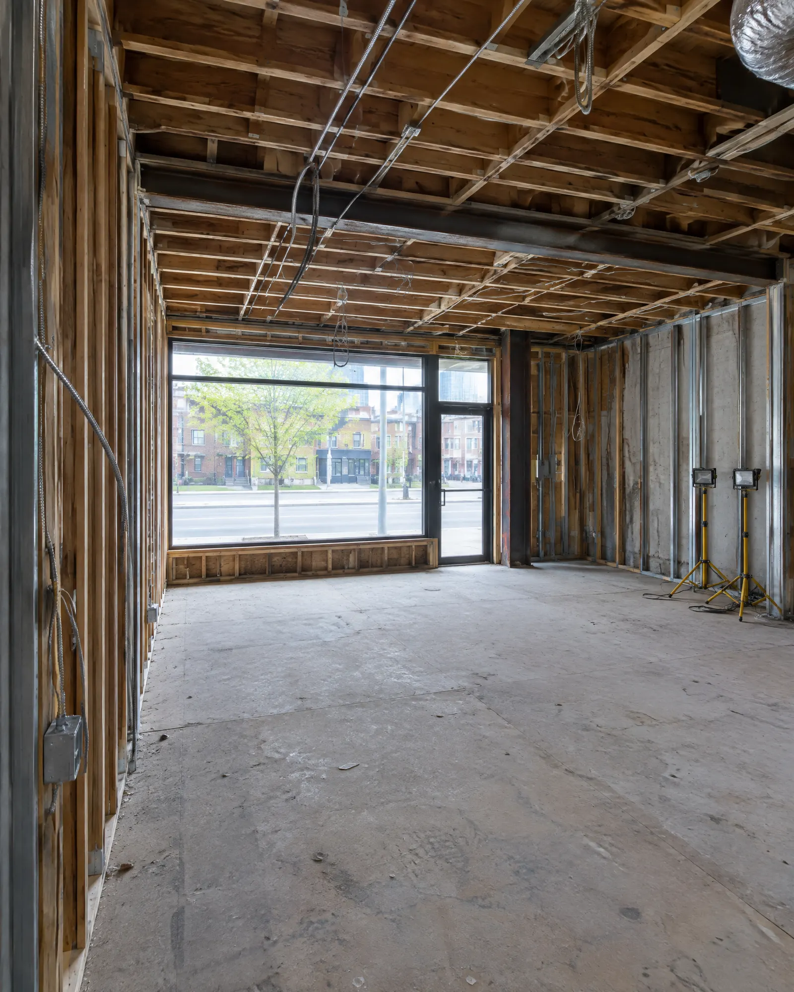 Gutted small commercial unit before build-out: exposed studs, bare subfloor